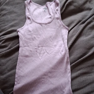Ljusrosa ribbad linnetopp - Säljer en söt ljusrosa ribbad linnetopp i mycket bra skick. Perfekt för sommardagar eller som ett lager under en tröja. Den ärmlösa designen gör den sval och bekväm att bära. Passar till både vardag och festliga tillfällen.