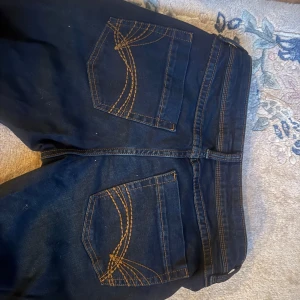 Mörkblå jeans från H&M - Säljer ett par mörkblå jeans från H&M i bra skick. De är tillverkade av 20% återvunnen bomull och har en klassisk femficksdesign med snygga sömmar på bakfickorna. Perfekta för vardagsbruk! De är lågmidjade