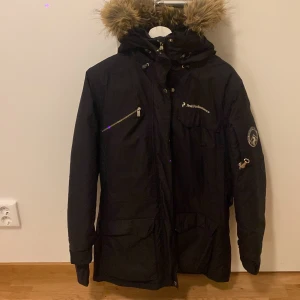 Svart vinterjacka från Peak Performance - Säljer en svart vinterjacka från Peak Performance i mycket bra skick. Jackan har en avtagbar huva med fuskpäls och flera praktiska fickor med dragkedjor. Perfekt för kalla vinterdagar! 🖤