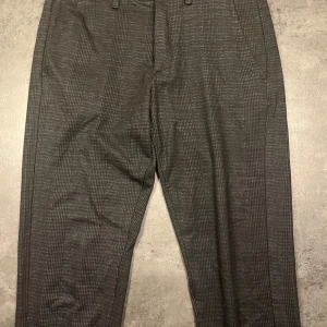 Grå rutiga kostymbyxor GABBA - Snygga grå kostymbyxor från GABBA med diskret rutmönster. Perfekta för både kontoret och festliga tillfällen. De har en klassisk passform med knappar och dragkedja i midjan. Materialet känns bekvämt och stilrent. Ett måste för garderoben! Och alldeles utmärks till jul och nyår! Nypris 1200:-