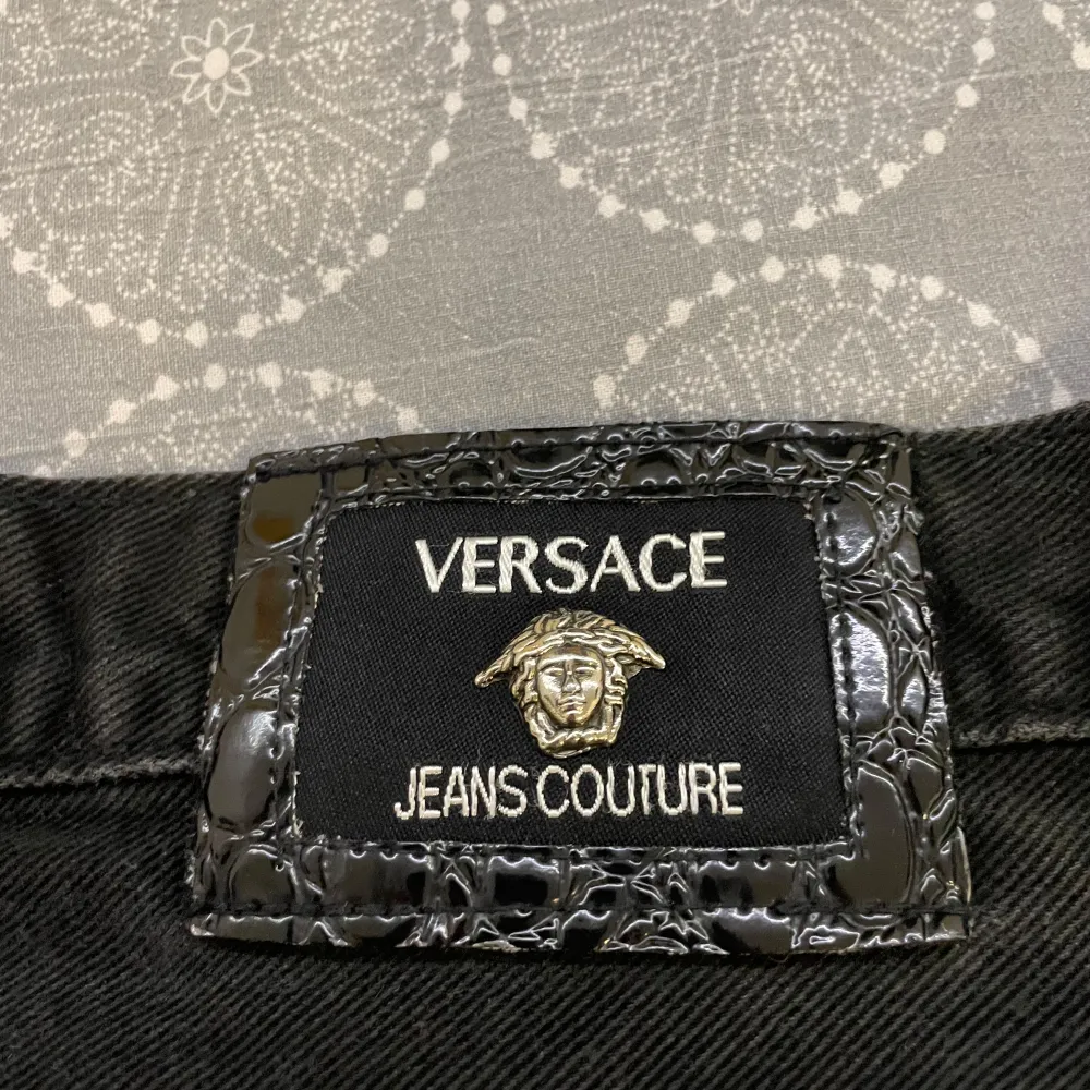 Säljer ett par snygga svarta jeans från Versace Jeans Couture. De har en klassisk femficksdesign och en stilren look med märkets logga på knappen och bakfickan. Perfekta för både vardag och fest!. Jeans & Byxor.