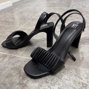 Svarta klackskor från LTX - Snygga svarta klackskor. De har en stilren design med en bred rem över foten och en smal rem runt hälen. Perfekta för festliga tillfällen eller en utekväll. Skorna har en bekväm klack. Endast använda en gång