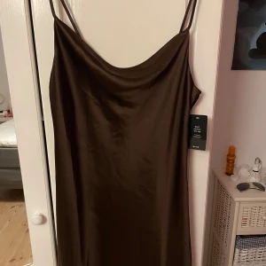 Satin mini dress - En brun glansig satin mini dress från  Na-kd. Helt ny och inte ens använd. Som ni ser på bilderna sitter prislappen kvar. 