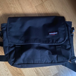 Eastpak väska - 40x22 eastpak axelväska i nästintill nytt skick ! Med en extra fick på insidan och två på utsidan, perfekt till skolan, arbetet eller bara till vardags! Både till herr och dam, nypris runt 500kr