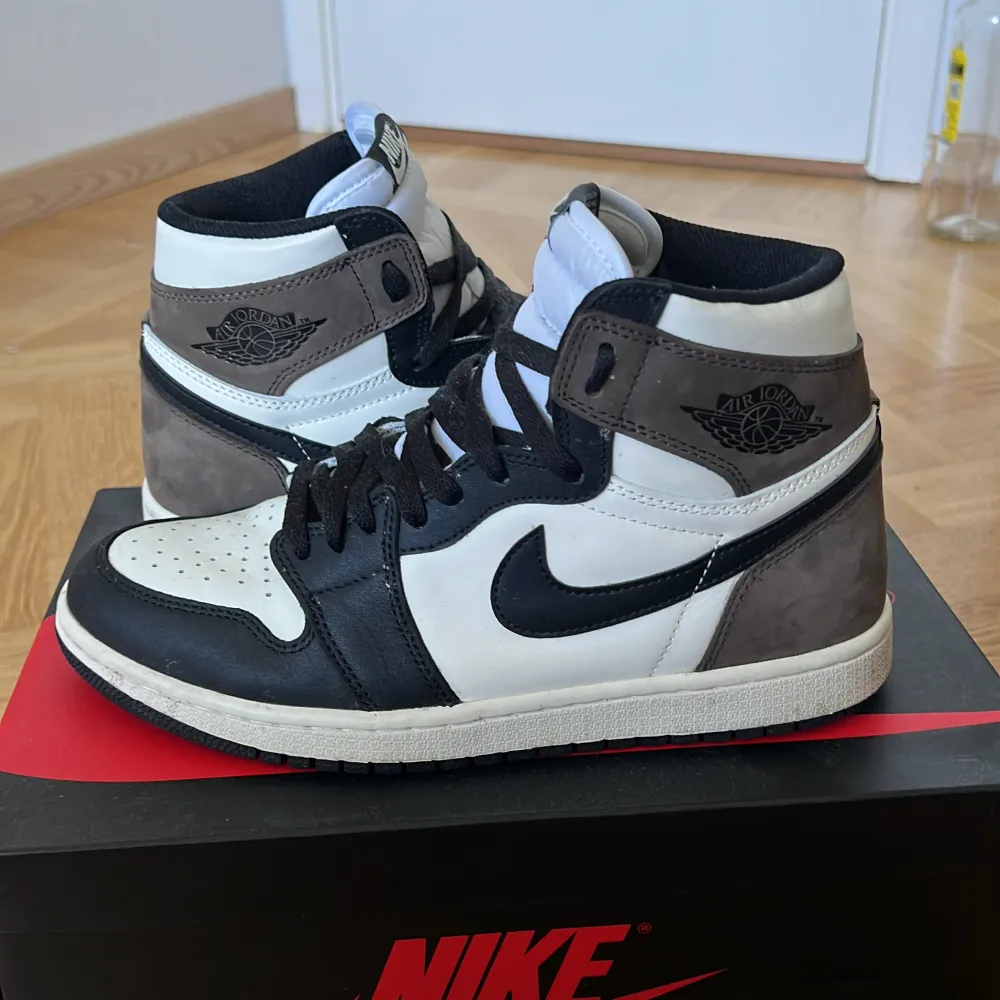 Säljer ett par Nike Air Jordans i färgerna svart, vit och brun. Skorna är i bra skick med lite slitage på sulan. De har en klassisk design med snörning och Nike-loggan på sidan. Perfekta för både vardag och träning. Vid snabb affär 750kr. Skor.