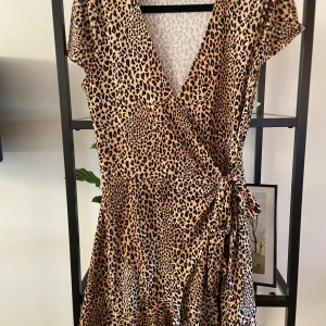 Leopardmönstrad omlottklänning från H&M - Säljer en superfin leopardmönstrad omlottklänning från H&M:s Divided-kollektion. Klänningen är kortärmad och har en knytning i midjan som ger en snygg passform. Perfekt för en fest eller en utekväll! 🐆
