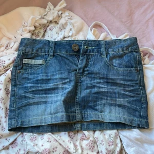 Jeanskjol från RANA - Säljer en snygg jeanskjol från BANNA i storlek S-XS. Kjolen är i blå denim med en klassisk femficksdesign och en knapp- och dragkedjestängning fram. Baksidan har två fickor med dekorativa sömmar och en liten logga. Perfekt för en avslappnad sommarlook! 💙TRYCK INTE KÖP NU!
