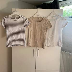 Säljer tre t-shirts i olika färger. Den första är vit med svarta ränder, den andra är beige och den tredje är vit. Alla t-shirts har korta ärmar och är gjorda av bomull. Perfekta för vardagsbruk! För alla tre 185 kr. Styckpris 80kr, köparen står för frakten.