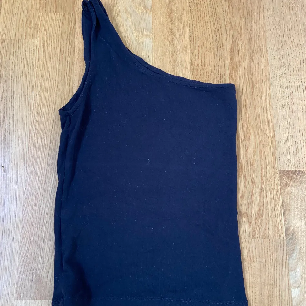 Säljer en stilren svart oneshoulder topp från Gina Tricot. Perfekt för en utekväll eller fest! Toppen är i ett mjukt och bekvämt material som sitter snyggt på kroppen.. Toppar.