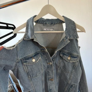 Jeansjacka NA-KD - Jeansjacka från NA-KD storlek 36. Aldrig använt. Öppna axlar och text på baksidan. 