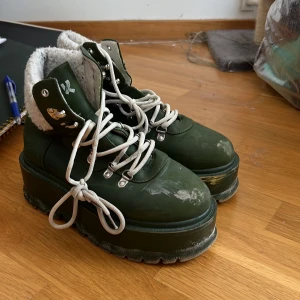 Gröna kängor med pälsfoder - Säljer ett par gröna kängor med vit snörning och pälsfoder. De har en rejäl platåsula och är perfekta för kalla dagar. Kängorna är i bra skick och redo för nya äventyr!