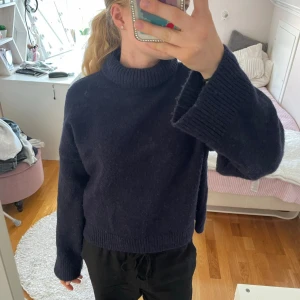 Mörkblå stickad tröja - Säljer en mysig mörkblå stickad tröja med polokrage. Tröjan är croppad och har långa ärmar, perfekt för höst och vinter. Den är i bra skick och superbekväm att ha på sig. Passar perfekt till både jeans och mjukisbyxor!