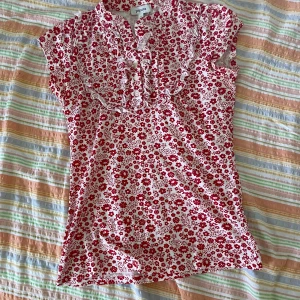 Blommig topp från Papaya - Säljer en superfin blommig topp från Papaya. Den är vit med röda blommor och har en söt volangdetalj framtill. Toppen är kortärmad och perfekt för sommardagar. Storlek 8, vilket motsvarar en medium.