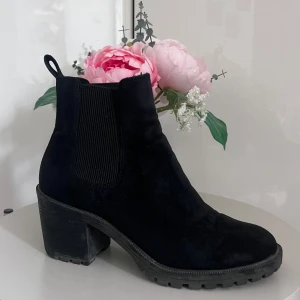 Svarta Chelsea boots i mocka - Säljer ett par snygga svarta Chelsea boots i mocka. De har en robust klack och elastiska paneler på sidorna för enkel på- och avtagning. Perfekta för höst och vinter!