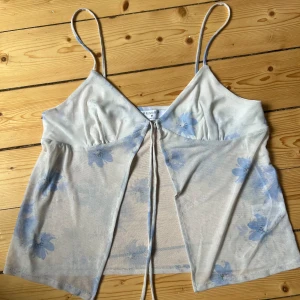 knytbar blommig top💕 - Supersöt top i skönt material! Blå och vitt blommigt mönster🤍🩵smått genomskinlig så funkar även med något under! storlek M men den passar S-L skulle jag säga. hör av er för mer bilder💕