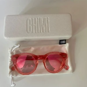 Rosa solglasögon från Chimi - Säljer ett par snygga rosa solglasögon från Chimi. De har en rund form och kommer med ett matchande fodral och en tygpåse för förvaring. Perfekta för att liva upp vilken outfit som helst!