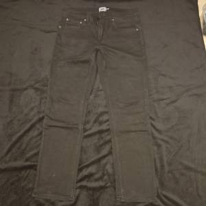 Snygga svarta jeansbyxor med en klassisk design. De har en normal passform och är perfekta för en stilren look. Byxorna har fem fickor och en knappgylf.
