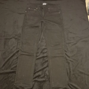 Svarta jeansbyxor - Snygga svarta jeansbyxor med en klassisk design. De har en normal passform och är perfekta för en stilren look. Byxorna har fem fickor och en knappgylf.