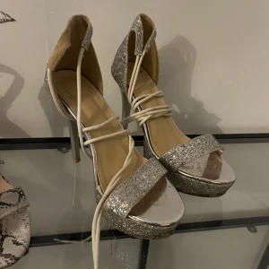 Glittriga silverpumps med snörning - Snygga pumps i silver med glittrig yta och snörning. Perfekta för en festlig kväll.