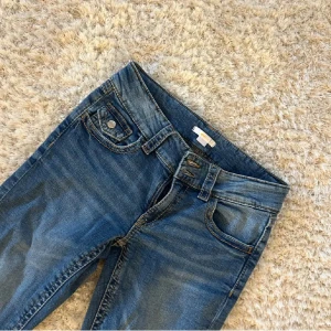 Blå jeans med bootcut - Snygga blå jeans med bootcut-stil och klassisk femficksdesign. Perfekta för en avslappnad look. De har en knapp och dragkedja framtill. De är använda 2 ggr, köpte på Plick men säljer 