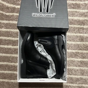 Svarta boots från Wildflower - Snygga svarta boots från Wildflower med dragkedja på sidan. Perfekta för en stilren look. Skorna har en robust sula med stjärnmönster för extra grepp. Helt may använd en gång.