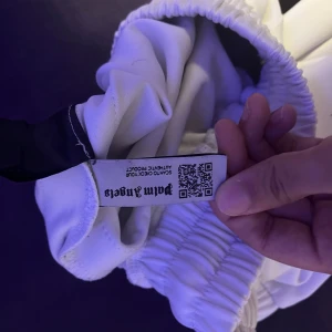 Vita byxor från Palm Angels - Snygga vita byxor från Palm Angels med elastisk midja och svarta detaljer längs sidorna. Perfekta för en stilren och avslappnad look.