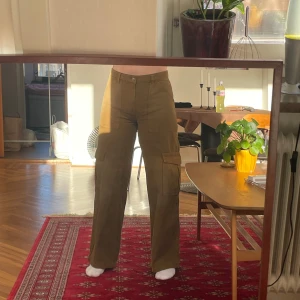 Bruna cargobyxor - Weekday - Snygga bruna cargobyxor med flera praktiska fickor och en loose passform. Perfekta för en avslappnad stil. Byxorna har en hög midja och är tillverkade i ett slitstarkt material.  Prislappen sitter fortfarande kvar.   WEEKDAY - Julian workwear trousers