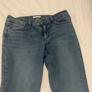 Blå jeans - Snygga blå jeans med klassisk design. De har en rak passform och femficksmodell med knapp och dragkedja framtill. Perfekta för en avslappnad stil. Utsvängda nedtill, och sitter bra. Använda 1 gång, nypris 499kr