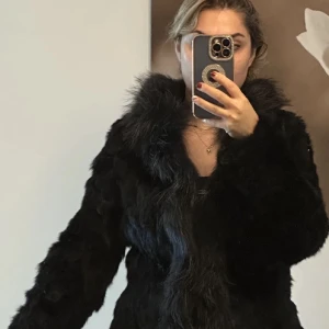 Svart pälsjacka - Snygg svart pälsjacka med fluffig textur och långärmad design. Perfekt för att hålla sig varm och stilren under kyliga dagar. Jackan har en klassisk look som passar till många olika outfits. Ny pris 5500 kr 