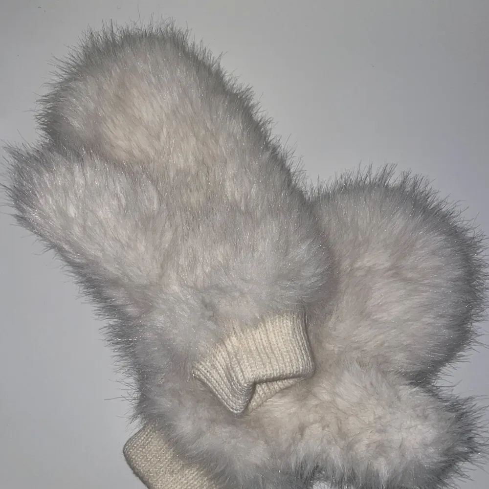 Stora mysiga och varma vita vantar med fluffig yta. Perfekta för kalla vinterdagar. De har en ribbstickad mudd vid handleden för extra komfort och värme.. Muu.