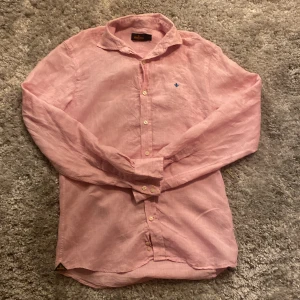 Rosa linneskjorta från Morris - Säljer en stilren rosa skjorta från Morris i 100% linne. Skjortan har långa ärmar och knappar framtill. Perfekt för en avslappnad men ändå elegant look. Skick 9/10 inga fläckar eller hål bara lite skrynklig. Nypris ~ 1500 mitt pris: 400 skriv gärna över frågor och funderingar, Priset kan diskuteras.
