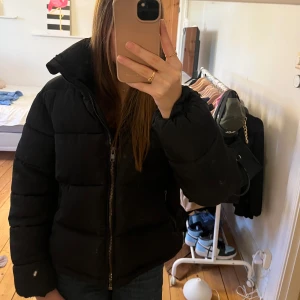 Snygg svart pufferjacka Glamorous - Säljer en supersnygg svart pufferjacka. Jackan har en hög krage och dragkedja framtill. Perfekt för kyliga dagar och är i superfint skick. Storlek: 36