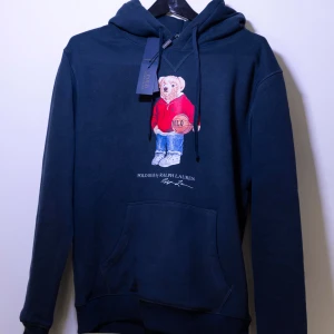 Ralph Lauren Hoodie - Helt ny Ralph Lauren Hoodie med en ikonisk nallebrodyr på framsidan. Hoodien har en klassisk passform med justerbar huva och en praktisk magficka. Perfekt för en avslappnad stil. Fler storlekar finns i min profil😊
