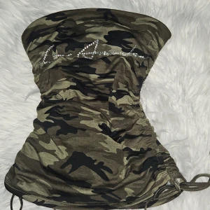 Camouflage tubtopp från Shein - Snygg camouflage tubtopp från Shein med glittrande detaljer framtill. Perfekt för en cool och avslappnad stil. Tillverkad i mjukt och stretchigt material för en bekväm passform. Inga diamanter saknas. Knappt använd. Max 2 ggr