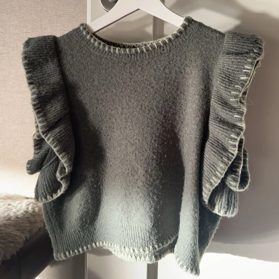 Grön stickad väst med volangdetaljer