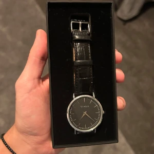 Svart klocka från When - Stilren klocka från When med svart urtavla och silverdetaljer. Klockan har ett svart läderarmband. Perfekt för en elegant look. Nypris: 1200kr. Skick 8/10, mer bilder och beskrivning finns om så önskas. Pris kan diskuteras:) Mvh/ Philip