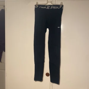 Svarta Nike Pro leggings - Snygga och bekväma svarta Nike Pro leggings med Dri-FIT-teknologi. Perfekta för träning med en tight passform och elastisk midja för extra komfort. Diskret Nike-logga på benet.