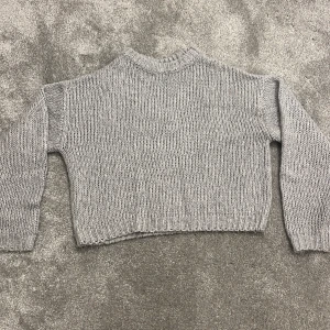 Grå stickad tröja från H&M Divided - Mysig grå stickad tröja från H&M Divided. Perfekt för kyliga dagar med sin ribbade design och långa ärmar. Enkel och stilren, passar till det mesta i garderoben.