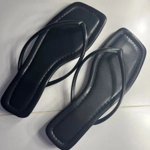 Svarta sandaler med fyrkantig tå - Stilrena svarta ”läder ”sandaler med fyrkantig tå och tunna remmar. Perfekta för en minimalistisk look under varma sommardagar.