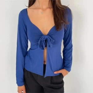Design by si mörkblå långärmad topp med knyt - Snygg blå långärmad topp med knyt framtill. Perfekt för en stilren look med en touch av elegans. Passar bra till både jeans och kjol.