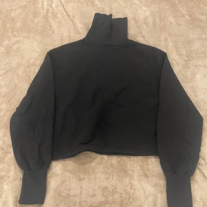 Polotröja  - Cropped svart polo hoddie, ifrån Nelly i storlek L. 