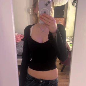 Svart ribbad topp från Gina Tricot - Säljer en stilren svart ribbad topp från Gina Tricot. Toppen har en tight passform och långa ärmar som är lite utsvängda