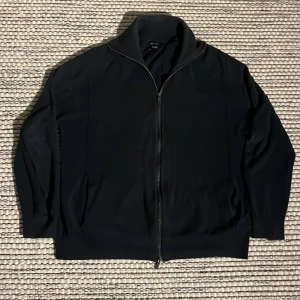 Mörk blå tröja med dragkedja från Massimo Dutti - Snygg svart tröja med dragkedja från Massimo Dutti. Perfekt för en stilren look med långärmad design och hög krage. Tillverkad i ett mjukt material för extra komfort. Tyvärr har ena inner fickan lossnat men det är inget som syns från utsidan eller effekterar tröjan