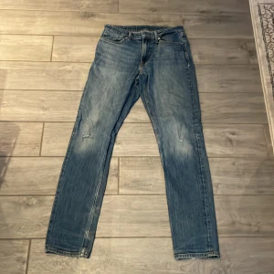 Blå jeansbyxor - Säljer ett par klassiska blå jeansbyxor med en rak passform. De har en dragkedja och knappar framtill samt fem fickor. Perfekta för en avslappnad stil.