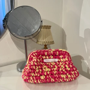 Handgjord sminkväska från Lemonloops - Unik handgjord necessär från Lemonloops i en härlig kombination av rosa och gul. Väskan är virkad med ett grovt mönster och har en klämma som stängning. Perfekt för att bära småsaker med stil.💕🍋