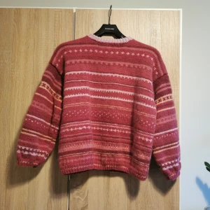 (XS / S) Rosa stickad tröja med mönster - Jättefin mysig stickad tröja med ett vackert mönster i olika nyanser av rosa och vitt. Uppskattas till en damstorlek XS/S. 🌸  Något mindre hål för huvudet och saknar stretch, så avråder om du vet med dig att du har ett större huvud... Jag har det och blir lite obekvämt när man ska dra på och av.. 😅  Osäker på material, men gissar på ull(?), lite stickig mot huden.