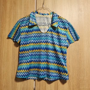 (M) Mönstrad topp i blått och gult, retro - En färgglad topp med zigzag-mönster i blått, gult och vitt. Själv använt som extra kul Sverige-tröja när det varit tid för sånt. Från XS-M beroende på hur tight man vill att den sitter. 🌸 Upptäckte en tråddragning bak (se sista bilden), men inget som stör helhetsintrycket. 