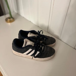 Svarta Adidas sneakers - Säljer ett par svarta Adidas sneakers med vita ränder och snörning. Skorna har en klassisk design och är perfekta för vardagsbruk. Sker såklart en tvätt innan leverans🤩