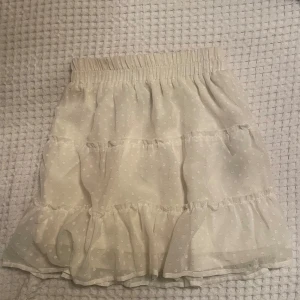 Vit prickig kjol  - Söt benvit kortkjol från New yorker med prickigt mönster och volangdetaljer. Kjolen har en elastisk midja för bekväm passform. Perfekt för en somrig look! I ett bra skick ⭐️storlek xs 
