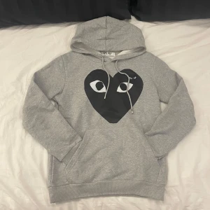 Cdg Hoodie - Hoodie från Comme des Garçons i storlek S. | Den är i utmärkt skick. | Den har en mindre broderad logga på vänster sida bröstet och ett större tryckt hjärta över framsidan av hela bröstet. | Det är bara att höra av sig om man har några frågor eller funderingar⭐️⭐️⭐️